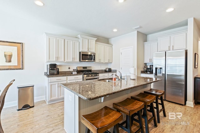 kitchen with stainless steel appliances, light hardwood / wood-style floors, and white cabinetry