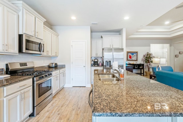 kitchen with light wood-type flooring, white cabinets, sink, a spacious island, and appliances with stainless steel finishes