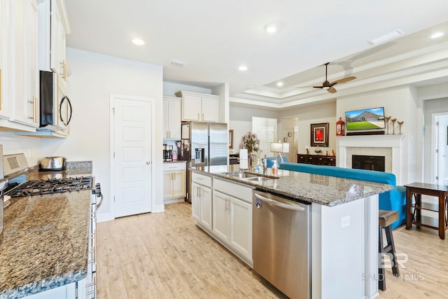 kitchen featuring stainless steel appliances, white cabinets, and a center island with sink