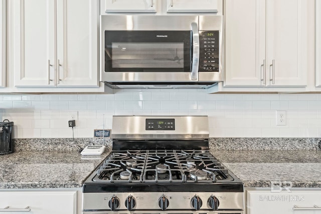 kitchen with appliances with stainless steel finishes, stone countertops, tasteful backsplash, and white cabinetry