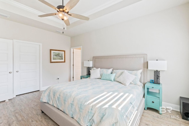 bedroom featuring light wood-type flooring, ceiling fan, a closet, and a raised ceiling