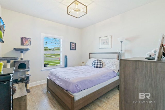 bedroom with light hardwood / wood-style flooring and a chandelier