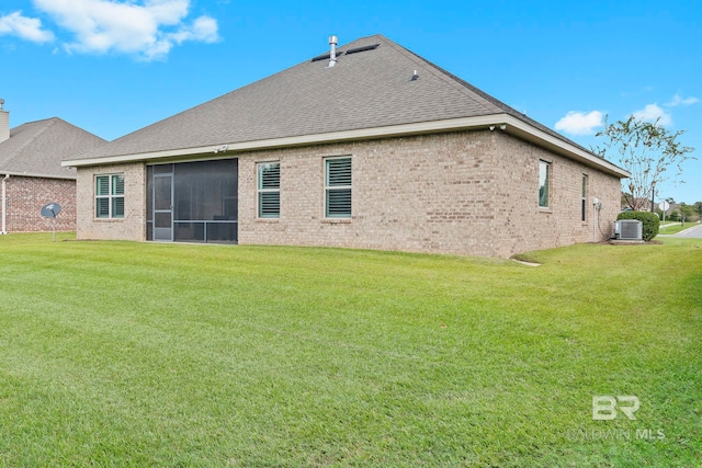 rear view of property with a sunroom, a lawn, and central AC