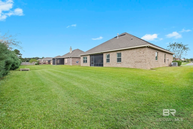 rear view of house featuring a sunroom, a lawn, and central air condition unit