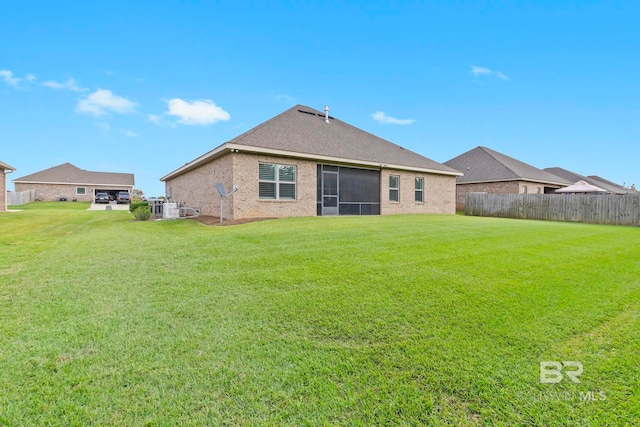 rear view of house featuring a yard and a sunroom