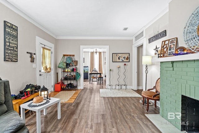 sitting room with crown molding, wood-type flooring, a notable chandelier, and a fireplace