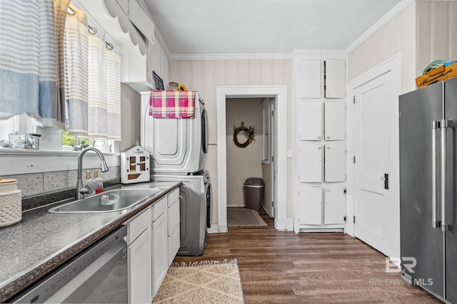 kitchen featuring sink, white cabinetry, ornamental molding, appliances with stainless steel finishes, and stacked washer / dryer