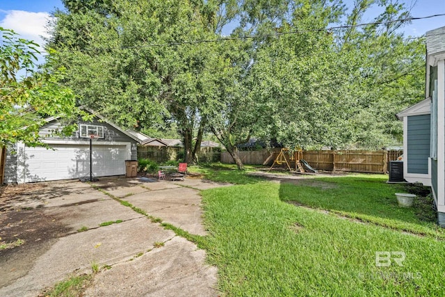 view of yard with a garage, cooling unit, an outbuilding, and a playground