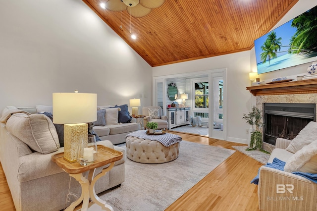 living room featuring a high end fireplace, light hardwood / wood-style floors, wooden ceiling, high vaulted ceiling, and ornamental molding