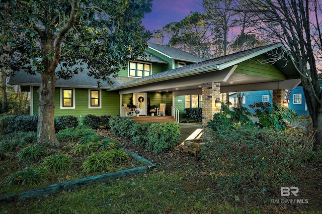 back house at dusk featuring a porch