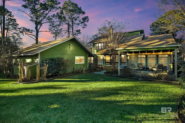 back house at dusk featuring a yard