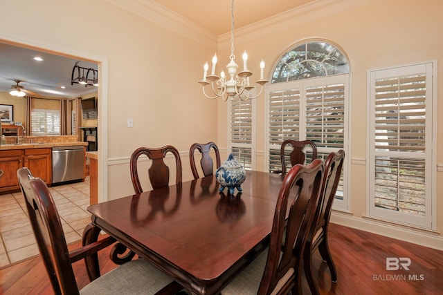 dining area featuring sink, light wood-type flooring, ceiling fan with notable chandelier, and ornamental molding