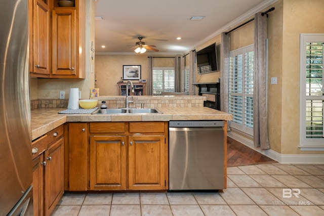 kitchen with ceiling fan, light tile patterned floors, sink, kitchen peninsula, and stainless steel appliances