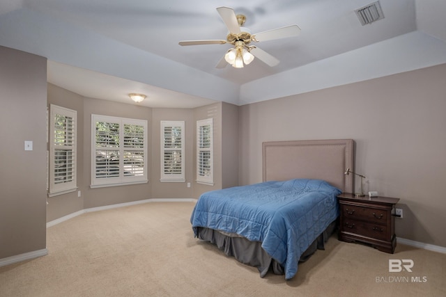 carpeted bedroom with ceiling fan and a tray ceiling