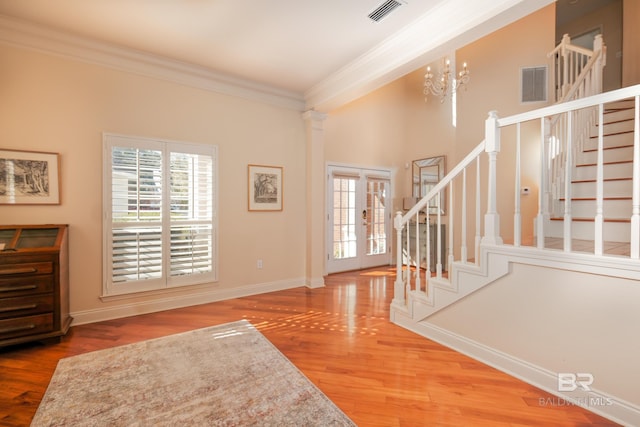 entryway with decorative columns, a chandelier, ornamental molding, and wood-type flooring