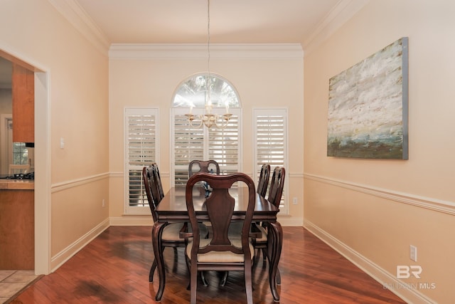 dining area with dark wood-type flooring, ornamental molding, and an inviting chandelier