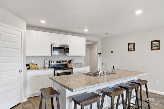 kitchen featuring sink, a breakfast bar area, an island with sink, stainless steel appliances, and white cabinets