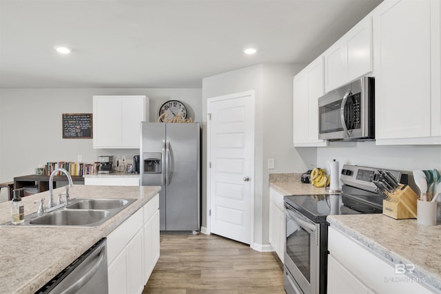 kitchen featuring white cabinetry, appliances with stainless steel finishes, sink, and wood-type flooring