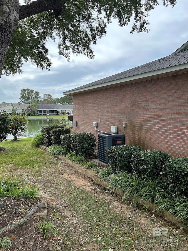 view of property exterior featuring central air condition unit and a water view