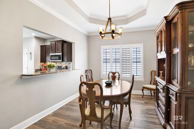 7122 Rocky Road Loop, Gulf Shores, AL 36542 - dining space featuring a tray ceiling, dark wood-style floors, baseboards, ornamental molding, and an inviting chandelier