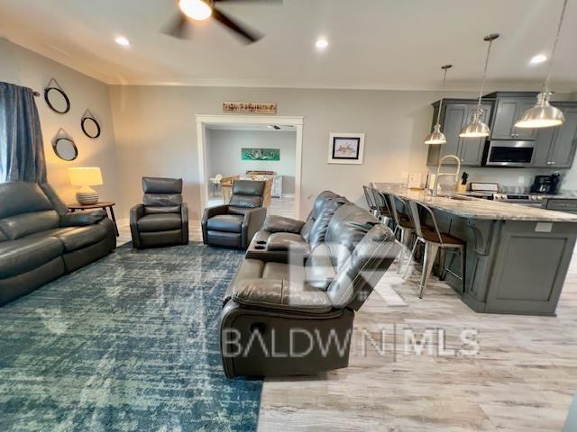 living room with ceiling fan, sink, and hardwood / wood-style floors