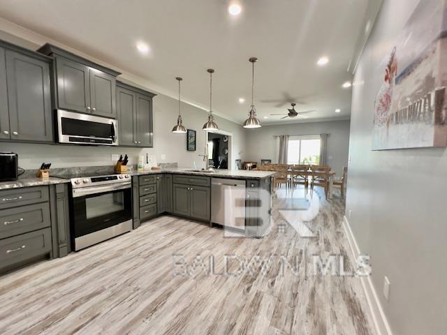 kitchen featuring kitchen peninsula, appliances with stainless steel finishes, ceiling fan, pendant lighting, and gray cabinets