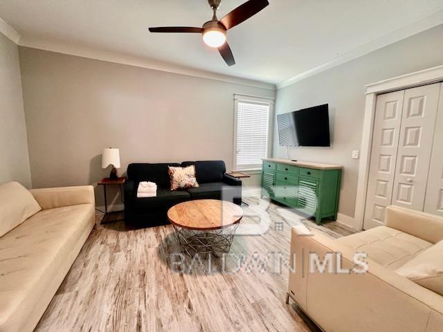 living room featuring ceiling fan, light hardwood / wood-style floors, and ornamental molding