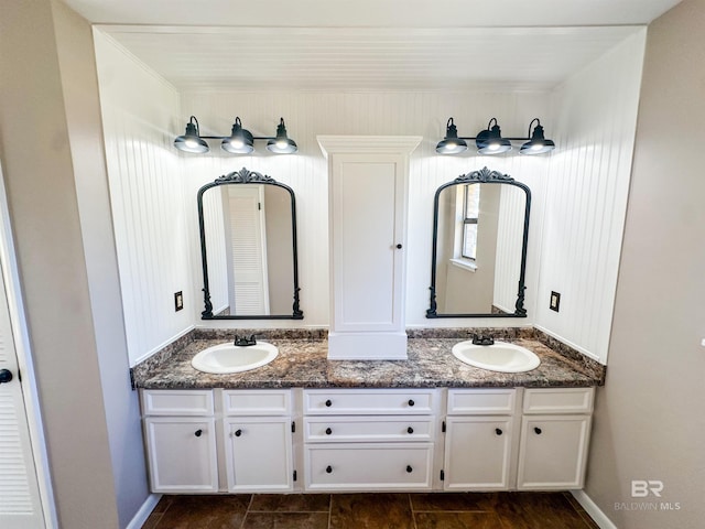 bathroom featuring a sink, baseboards, and double vanity