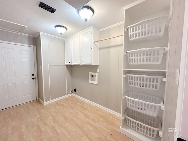 clothes washing area with washer hookup, visible vents, ornamental molding, cabinet space, and light wood finished floors