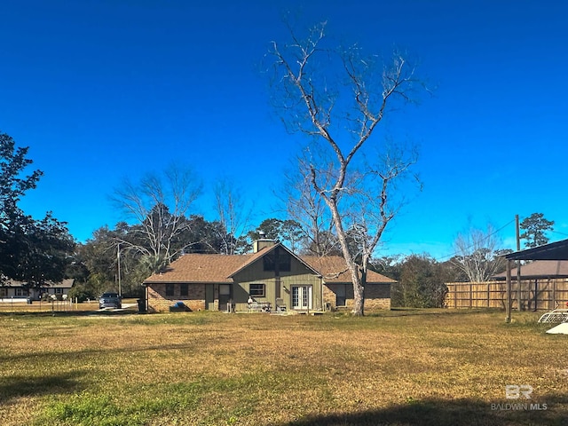 rear view of house featuring a yard and fence