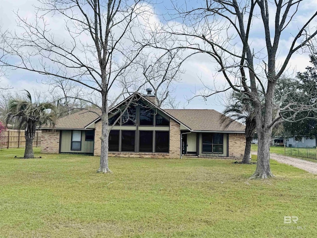 1104 N Pine St, Foley, AL 36535 - view of front of house with brick siding, a front yard, roof with shingles, a chimney, and driveway
