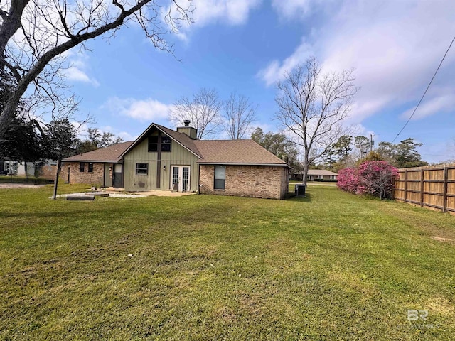 1104 N Pine St, Foley, AL 36535 - rear view of property featuring fence, a chimney, a lawn, a patio area, and brick siding