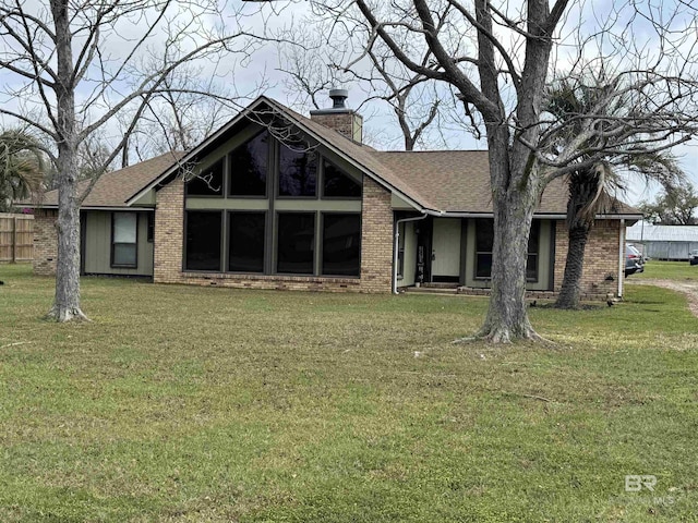 1104 N Pine St, Foley, AL 36535 - view of front facade featuring a shingled roof, a front lawn, brick siding, and a chimney