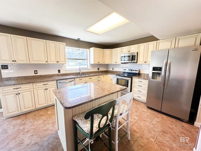 kitchen with a breakfast bar area, dark stone countertops, a center island, stainless steel appliances, and a sink