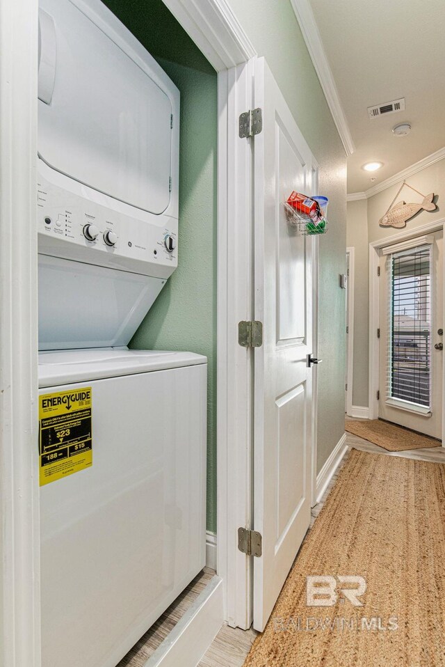 17290 Perdido Key Dr Unit 5B, Pensacola, FL 32507 - washroom featuring stacked washer and clothes dryer, crown molding, visible vents, laundry area, and baseboards