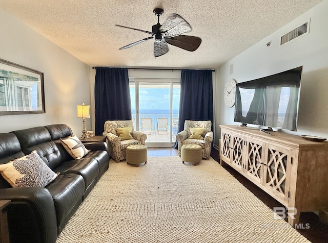 living room with a textured ceiling, ceiling fan, and visible vents