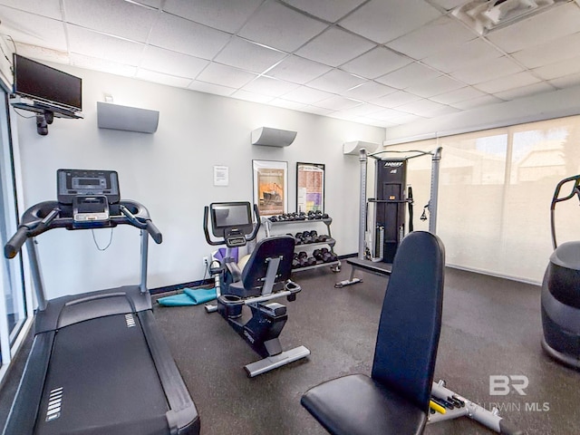 gym with baseboards, a paneled ceiling, and visible vents