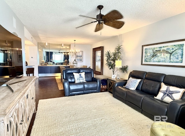 living room with ceiling fan with notable chandelier and a textured ceiling