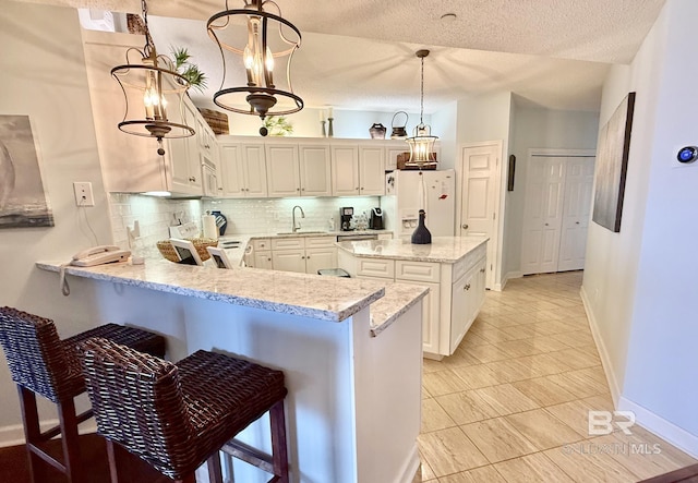kitchen featuring decorative backsplash, a kitchen island, baseboards, white refrigerator with ice dispenser, and a sink