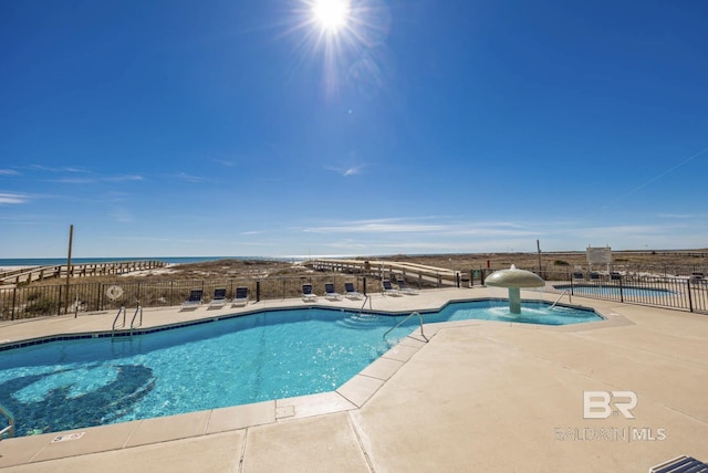 view of swimming pool with pool water feature, a water view, and a patio area