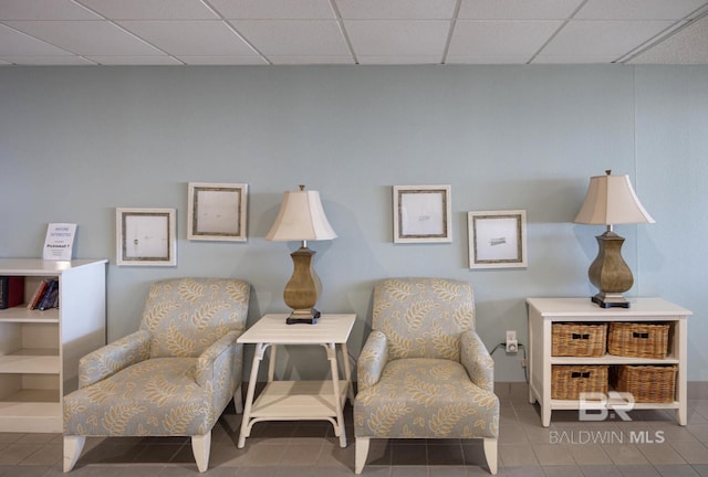 living area with tile patterned flooring and a paneled ceiling