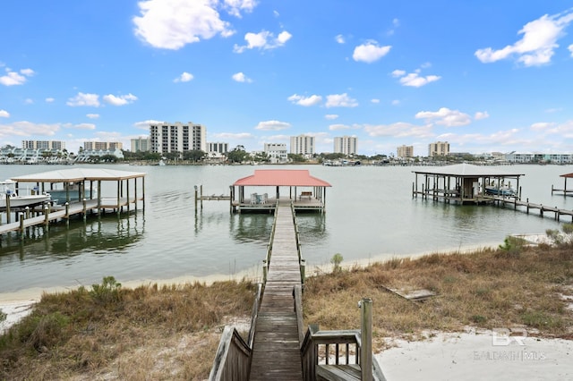 view of dock with a water view, boat lift, and a city view