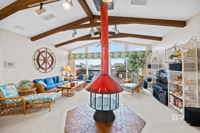 living room with a wood stove, vaulted ceiling with beams, visible vents, and carpet flooring