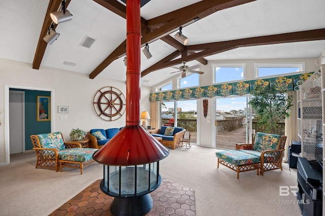 sunroom featuring visible vents, ceiling fan, vaulted ceiling with beams, rail lighting, and a wood stove