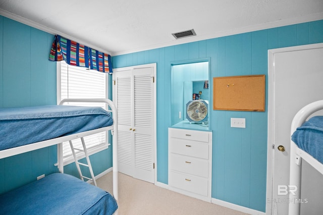 carpeted bedroom featuring ornamental molding, a closet, visible vents, and baseboards