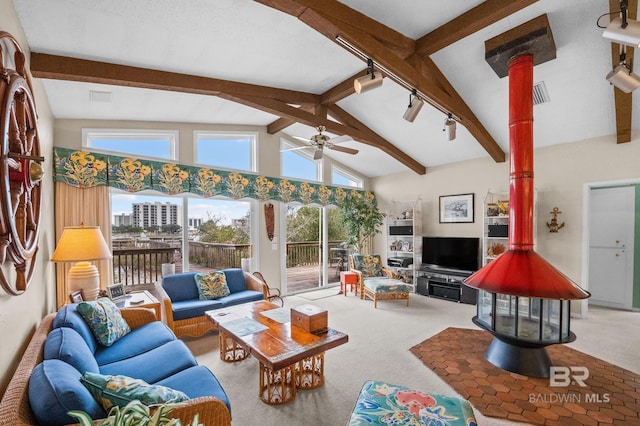 living area featuring a ceiling fan, a wood stove, carpet flooring, and lofted ceiling with beams