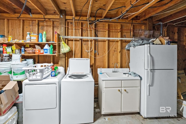 laundry area featuring separate washer and dryer, a sink, cabinet space, and wooden walls