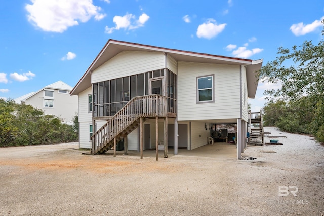 back of house featuring a carport, a sunroom, and stairway