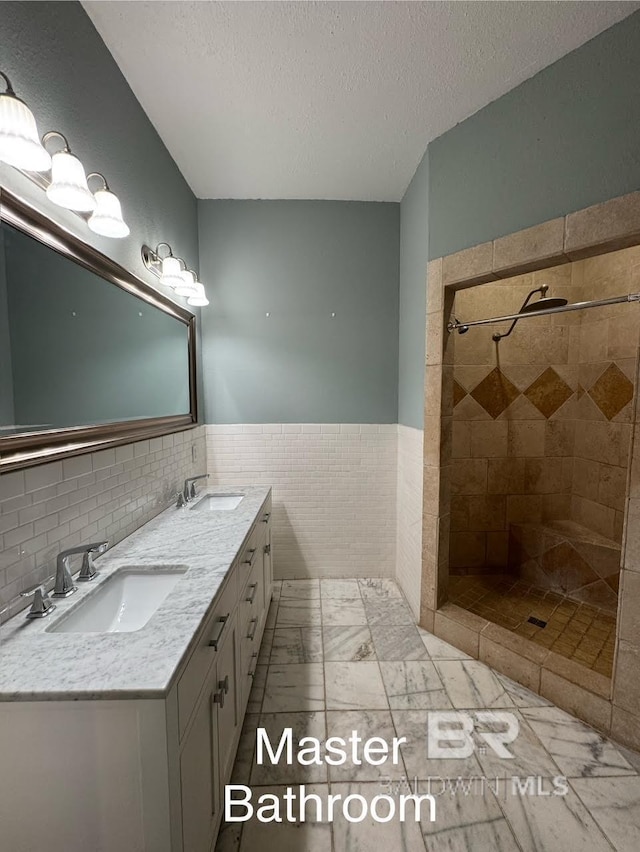 253 Cherokee St, Mobile, AL 36606 - bathroom with tile walls, a textured ceiling, tiled shower, double vanity, and wainscoting