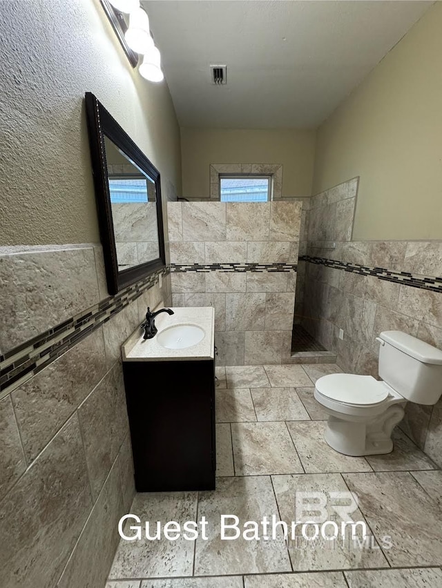 253 Cherokee St, Mobile, AL 36606 - full bath with tile walls, toilet, walk in shower, vanity, and a wainscoted wall